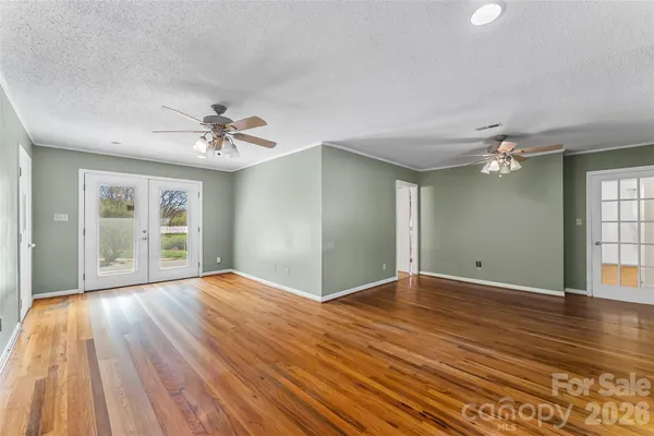 a view of an empty room with a window and wooden floor