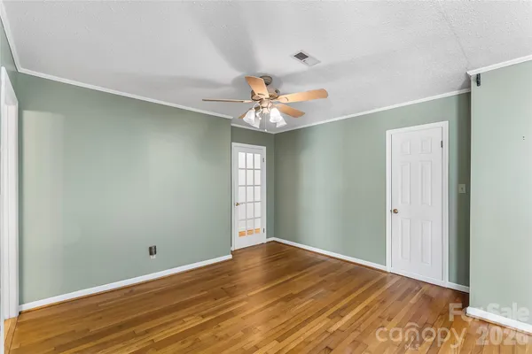 a view of a room with a chandelier fan and wooden floor