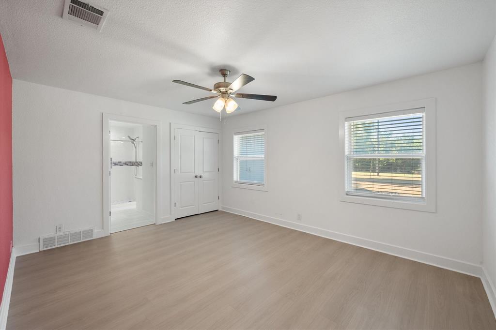 917 Goodwyn Road Italy, TX 76651 - Photo 20 of 40 Spacious interior featuring wood-finish flooring, two windows, a ceiling fan with integrated lighting, and a closet with double bifold doors