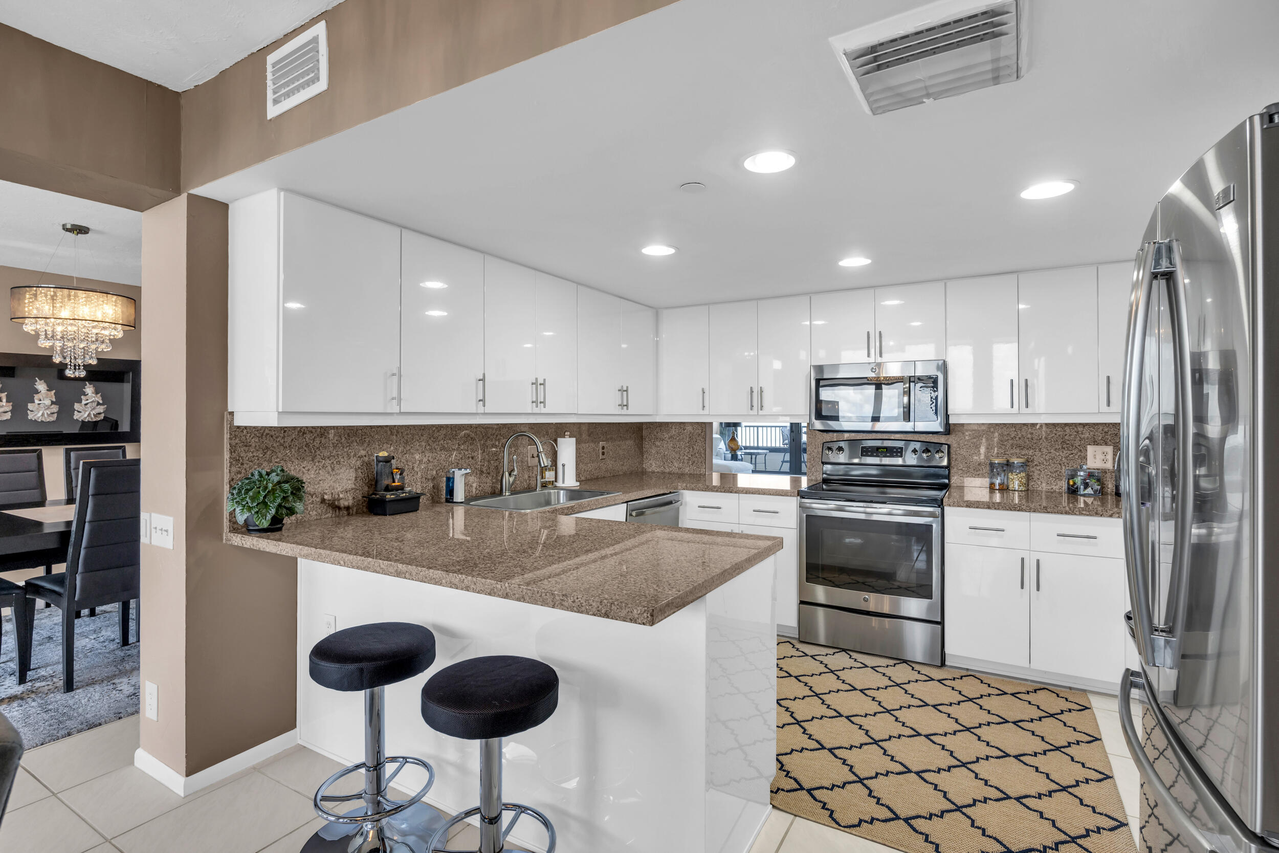 19900 South Beach Road, Unit 503 Jupiter, FL 33469 - Photo 27 of 51 a kitchen with stainless steel appliances kitchen island granite countertop a refrigerator and a stove top oven with white cabinets