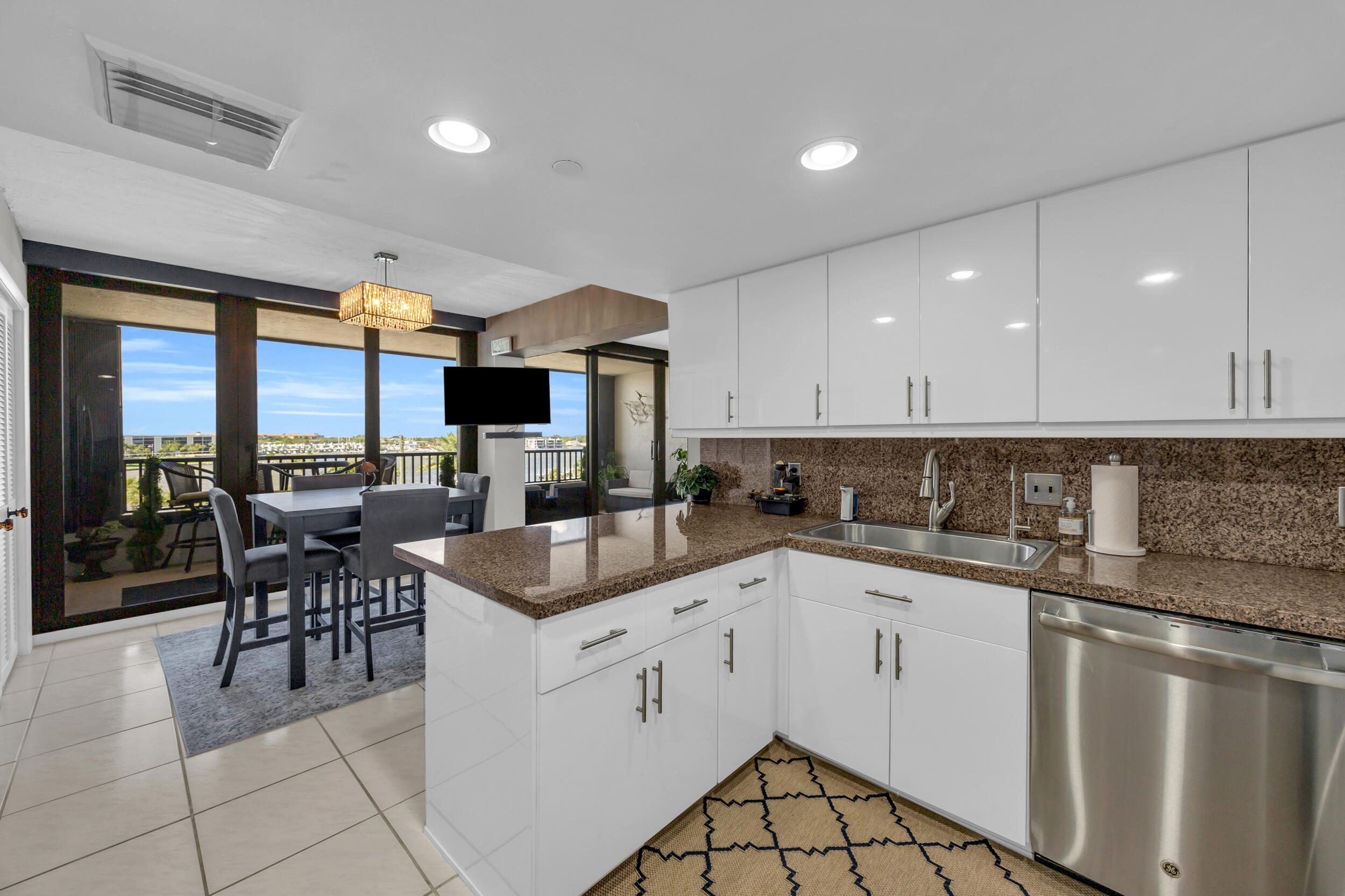 19900 South Beach Road, Unit 503 Jupiter, FL 33469 - Photo 28 of 51 a kitchen with a sink white cabinets and glass table chairs