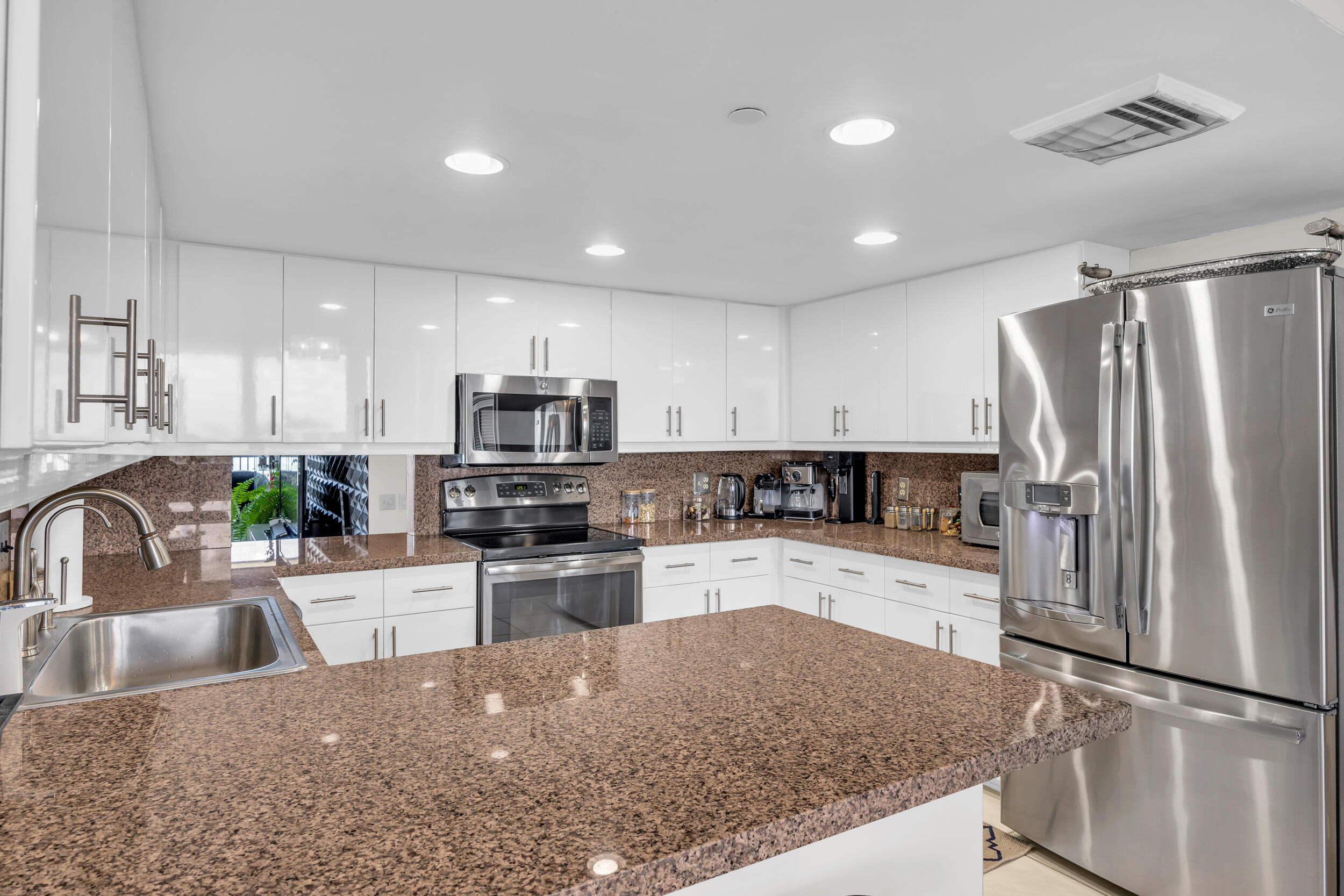 19900 South Beach Road, Unit 503 Jupiter, FL 33469 - Photo 29 of 51 a kitchen with a refrigerator a sink a stove top oven a refrigerator and white cabinets with wooden floor