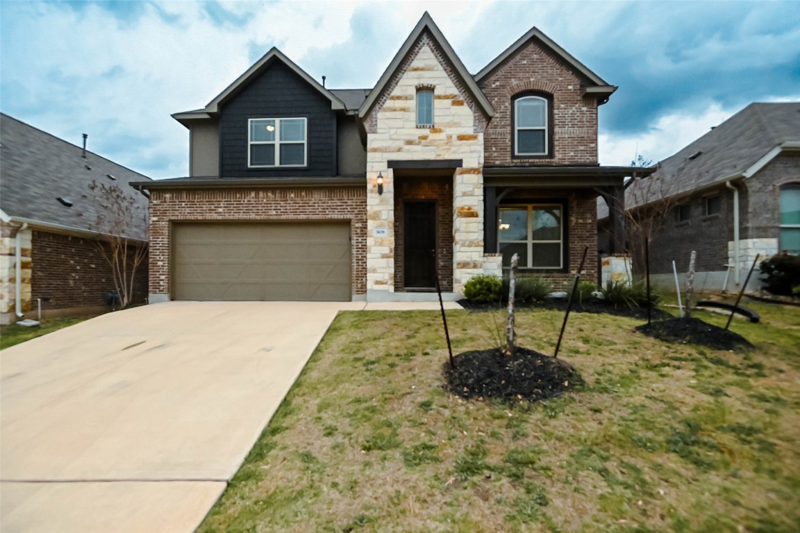 908 Leadtree Loop Buda, TX 78610 - Photo 1 of 1 View of front facade featuring concrete driveway, an attached garage, stone siding, a front yard, and brick siding