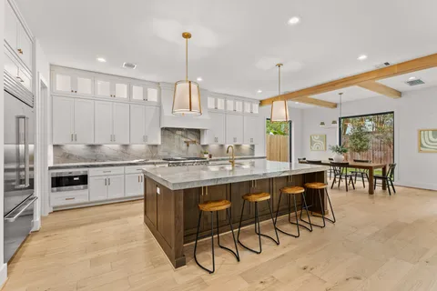a kitchen with stainless steel appliances granite countertop a stove top oven a sink dishwasher a dining table and chairs with wooden floor