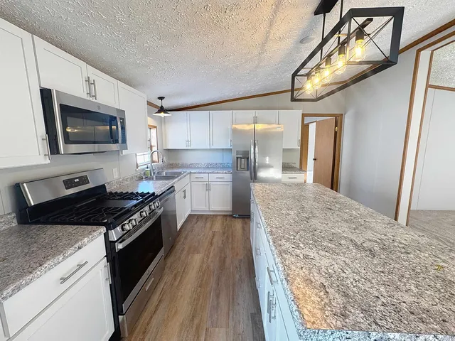 a kitchen with stainless steel appliances granite countertop a stove a sink and a microwave