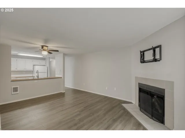 a view of an empty room with wooden floor and a fireplace