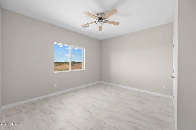 an empty room with ceiling fan and window
