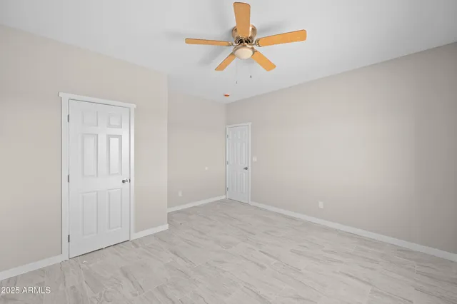 an empty room with wooden floor and ceiling fan