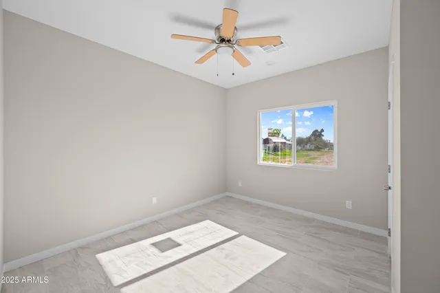 an empty room with chandelier fan and windows