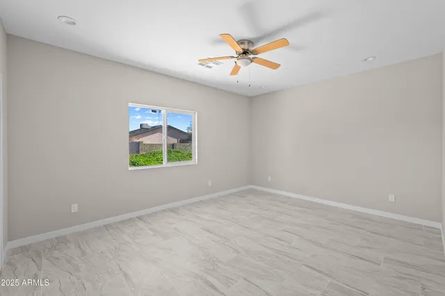 an empty room with window and ceiling fan