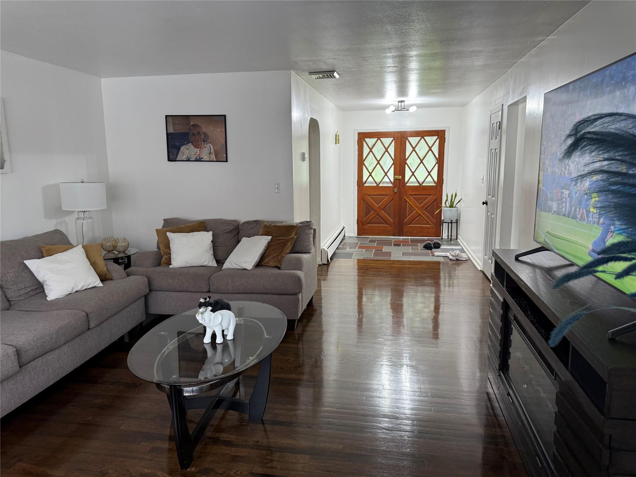 77 Upper Road Middletown, NY 10940 - Photo 3 of 18 Living room with arched walkways, a baseboard heating unit, and dark wood-type flooring