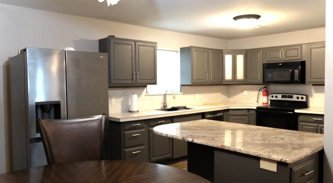 415 Martin Street Muskogee, OK 74401 - Photo 4 of 6 Kitchen featuring gray cabinetry, stainless steel refrigerator, black range, and an island with a stone countertop