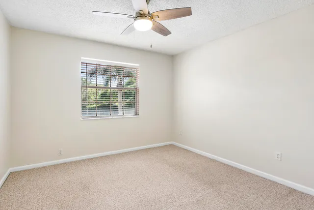 an empty room with a window and a fan