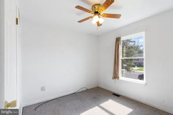a view of empty room with wooden floor and ceiling fan