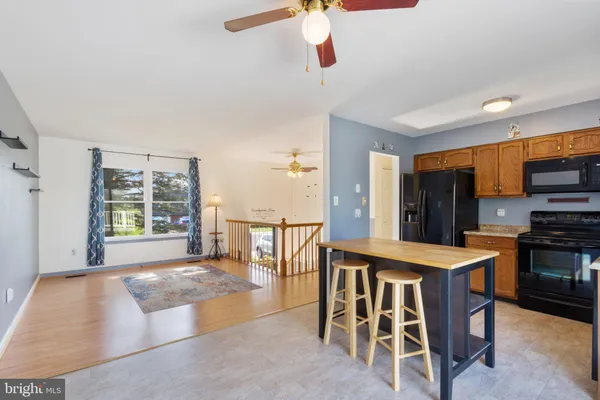 a open kitchen with stainless steel appliances kitchen island granite countertop a table and chairs in it