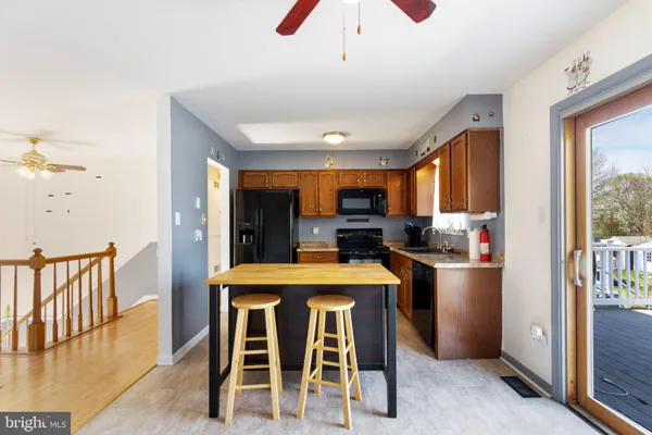 a kitchen with stainless steel appliances kitchen island granite countertop a refrigerator a stove top oven a sink dishwasher and white cabinets with wooden floor