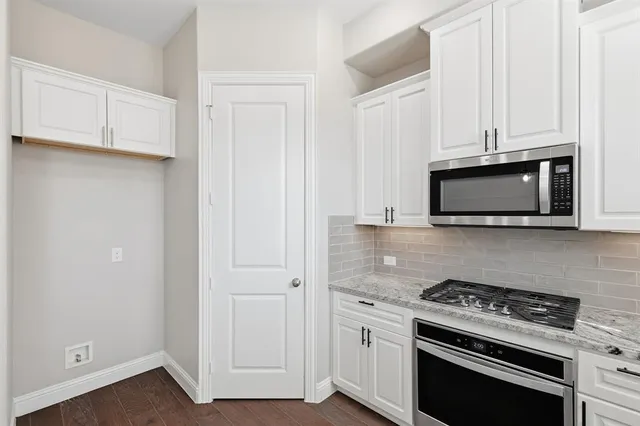 an empty room with chandelier fan and windows