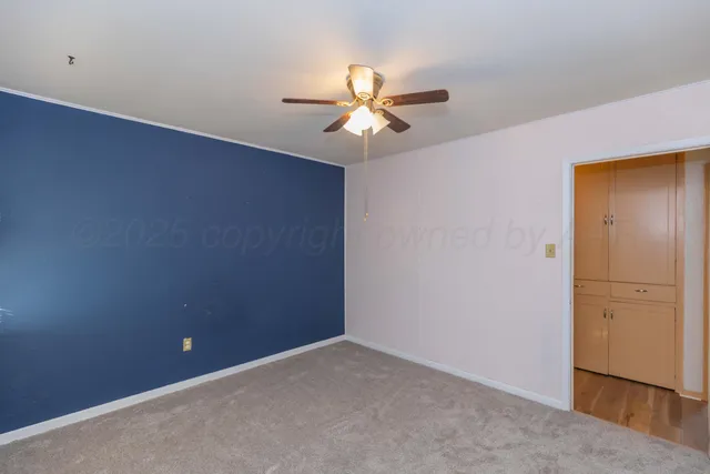 an empty room with closet and a chandelier fan