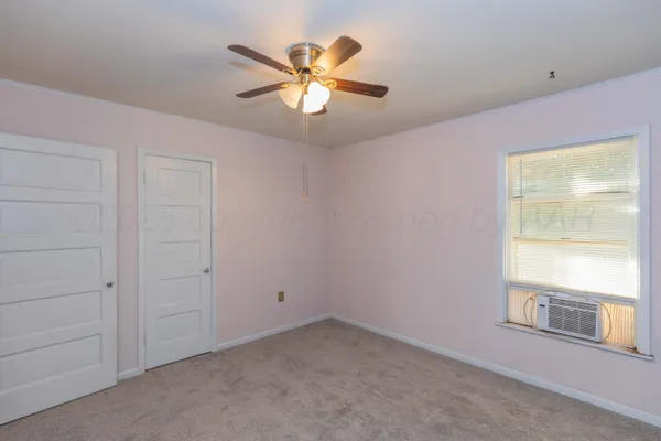an empty room with windows and fan