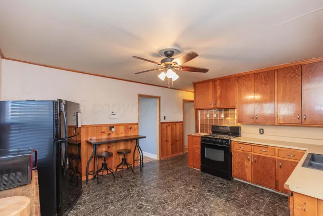 a kitchen with stainless steel appliances kitchen island granite countertop a stove refrigerator and cabinets