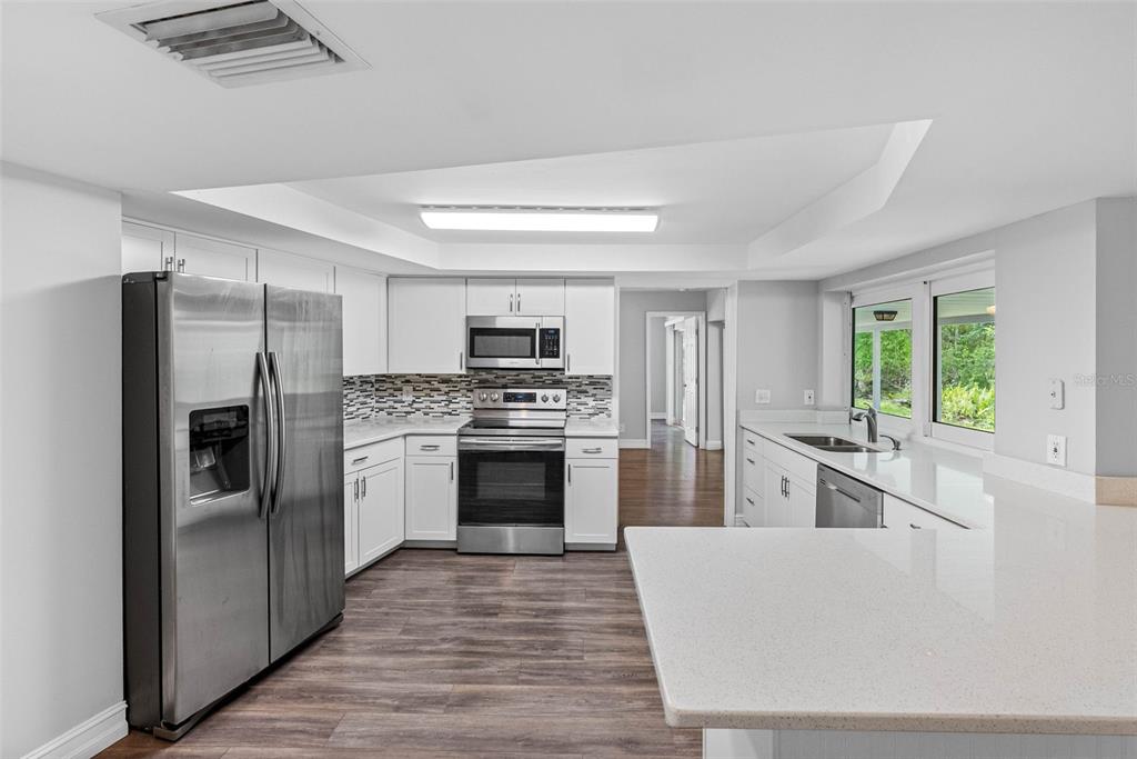 346 Ranch Road Tarpon Springs, FL 34688 - Photo 39 of 64 a kitchen with white cabinets and stainless steel appliances