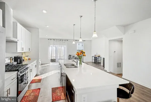 a large kitchen with kitchen island a stove a sink a center island and furniture