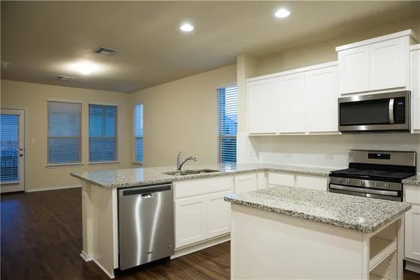 a kitchen with granite countertop a sink and a stove top oven with wooden floor