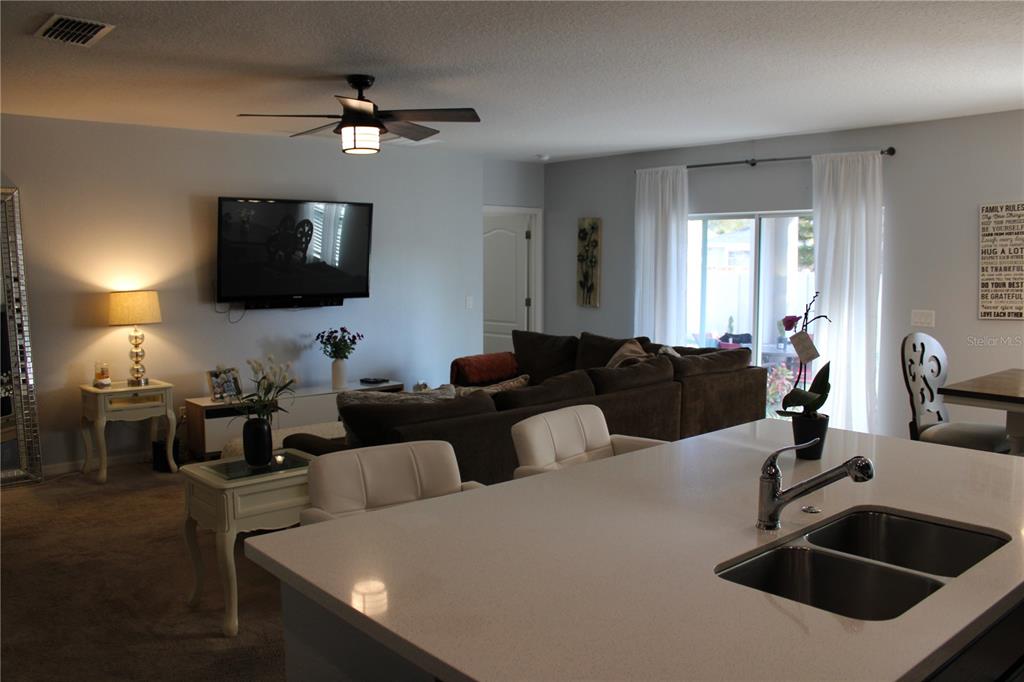 2591 Wadeview Loop St. Cloud, FL 34769 - Photo 5 of 18 a living room with furniture a flat screen tv and kitchen view