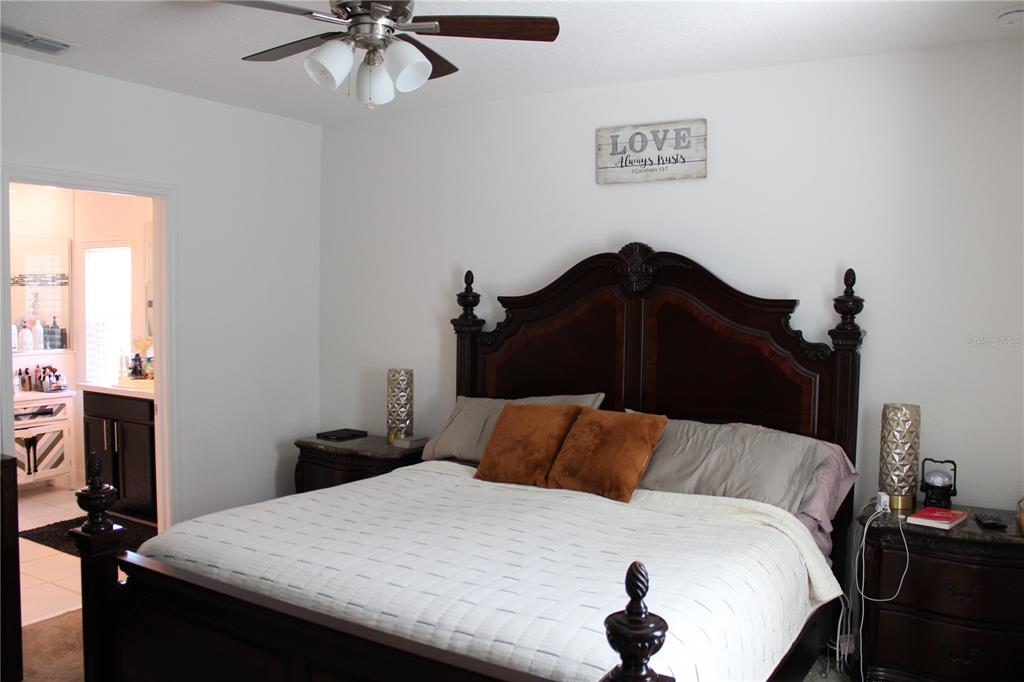 2591 Wadeview Loop St. Cloud, FL 34769 - Photo 8 of 18 a bedroom with a bed and a chandelier