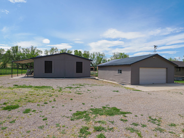 94 Spring Canyon Road Coalville, UT 84017 - Photo 14 of 50 Property featuring two detached structures: a gray outbuilding with a covered patio area and a separate garage building with a concrete drive