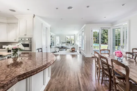 a dining room with stainless steel appliances granite countertop a stove top oven a dining table and chairs with wooden floor