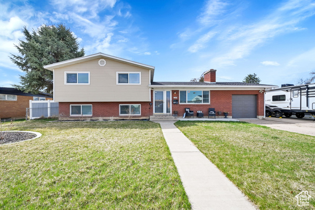 2149 West 4850th Street South Roy, UT 84067 - Photo 1 of 1 Tri-level home with brick siding, a chimney, a garage, and concrete driveway