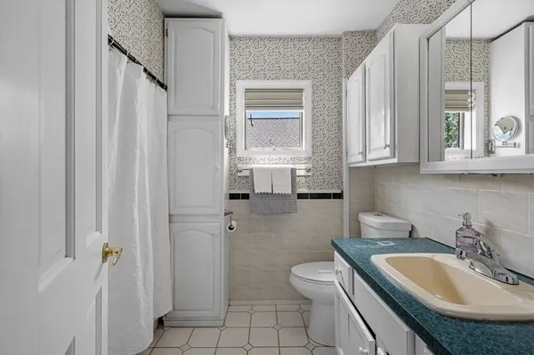 a bathroom with a sink a toilet a window and shower