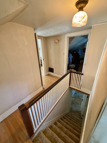 a view of a hallway with wooden floor and stairs