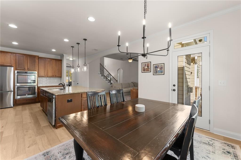 8055 Veranda Curve Ball Ground, GA 30107 - Photo 23 of 65 a kitchen with stainless steel appliances granite countertop a kitchen island a stove a refrigerator a sink a dining table and chairs with wooden floor
