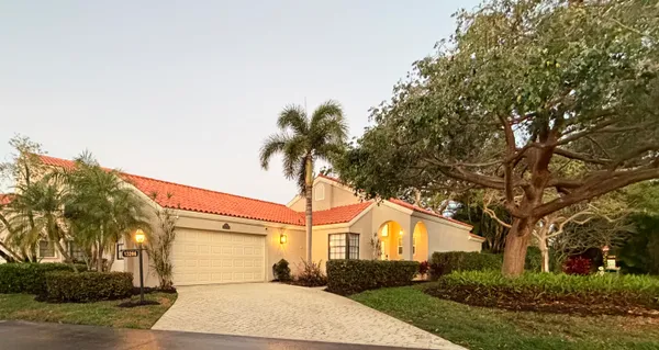 a front view of a house with a garden and trees