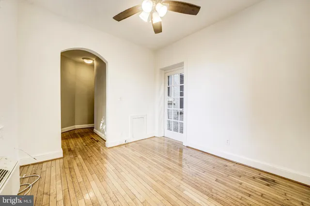 an empty room with wooden floor cabinet and windows