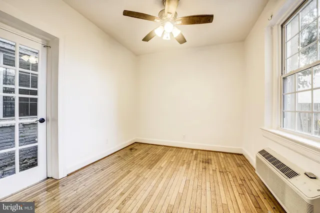 a view of empty room with wooden floor and fan