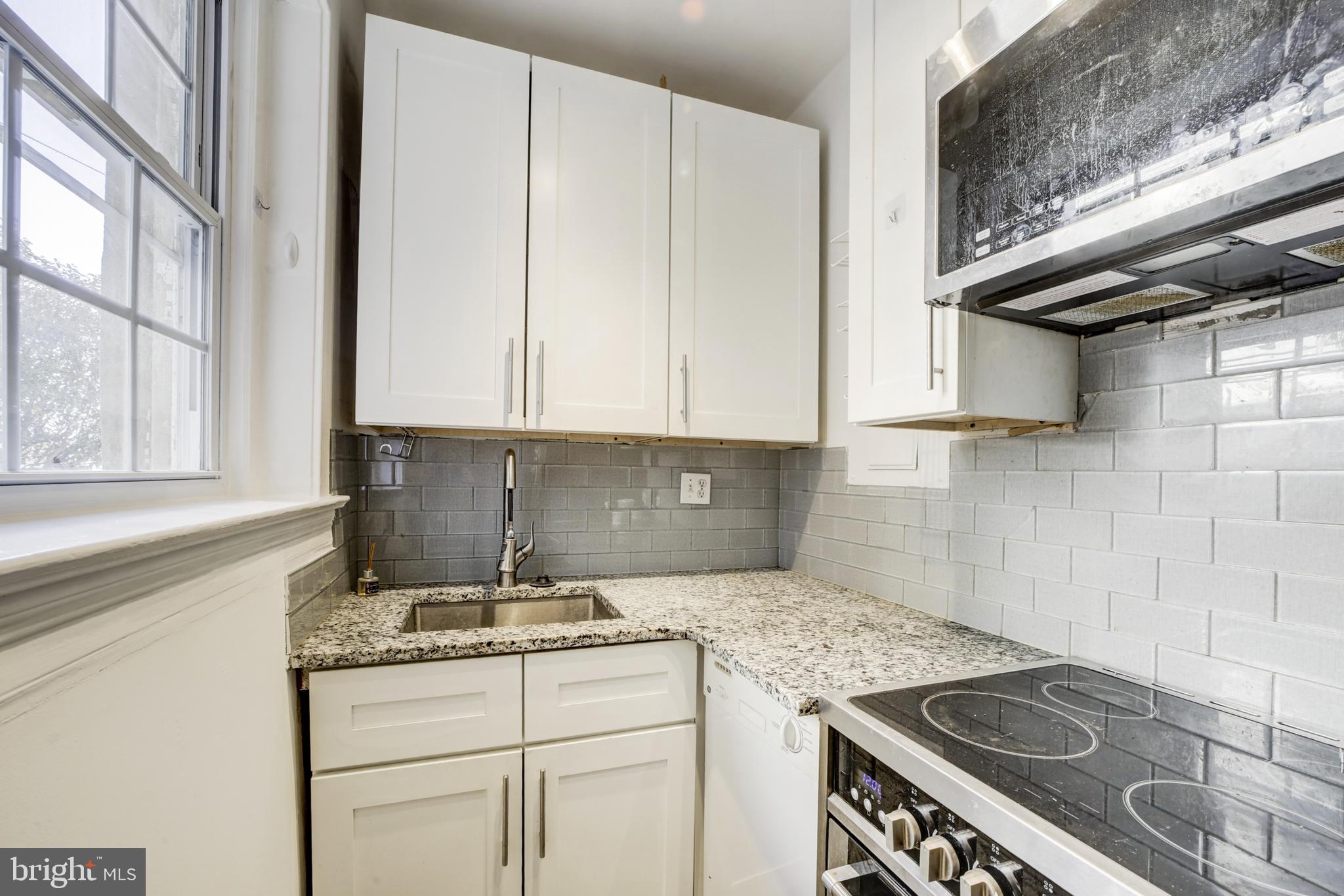 3520 W Place Northwest, Unit 103 Washington, DC 20007 - Photo 7 of 13 a kitchen with granite countertop a sink stove and cabinets