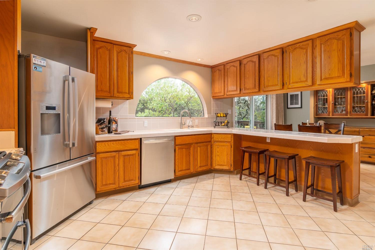 a kitchen with stainless steel appliances granite countertop a refrigerator a sink a stove with wooden cabinets