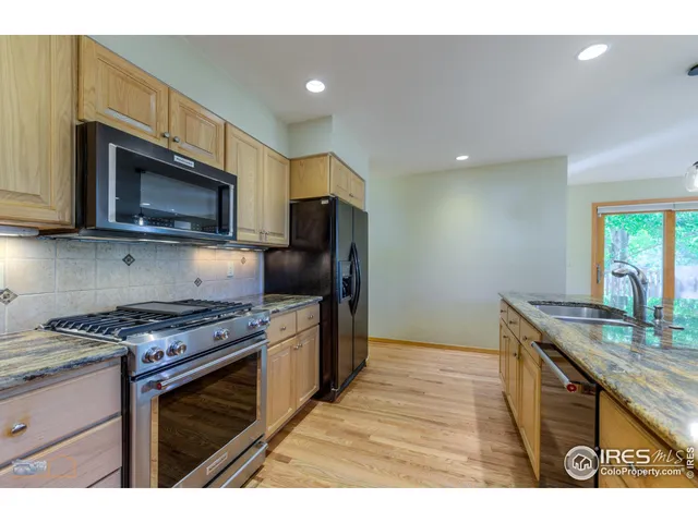 a kitchen with granite countertop a stove top oven microwave and refrigerator