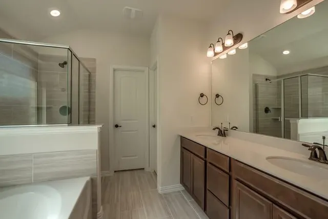 a bathroom with a double vanity sink a large mirror and shower