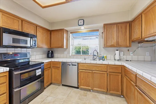 a kitchen with stainless steel appliances granite countertop wooden cabinets stove top oven and sink