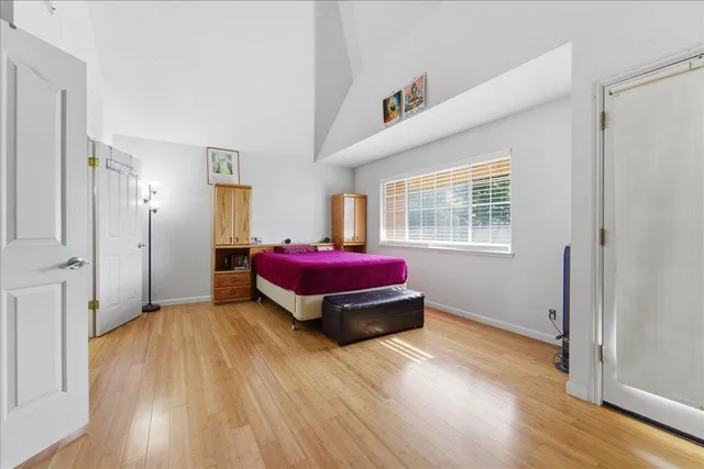 a spacious bedroom with a bed and wooden floor