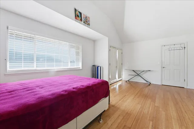a bed sitting in a bedroom next to a window and a wooden floor