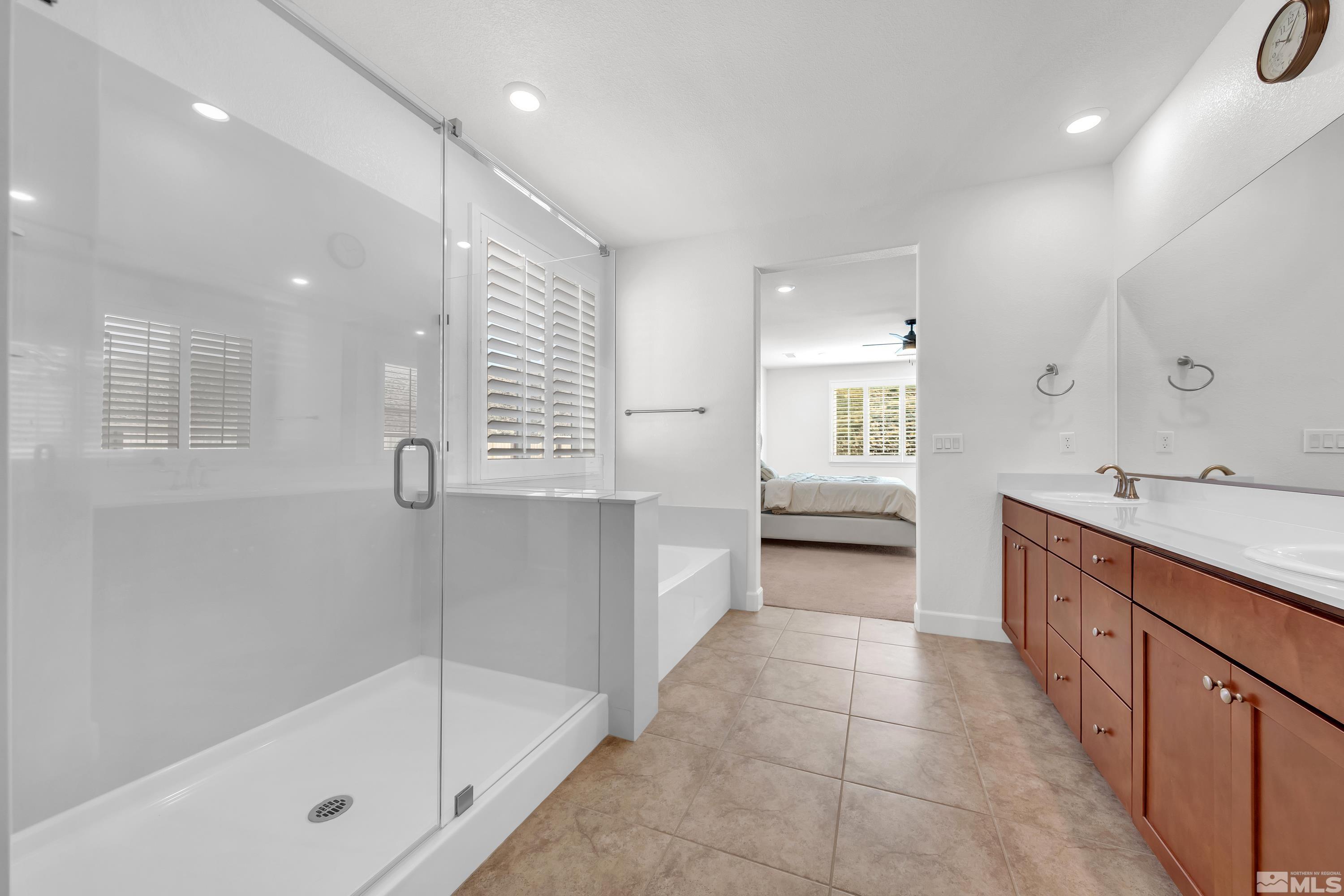 10310 Alchemy Way Reno, NV 89521 - Photo 17 of 30 a bathroom with a bathtub a double vanity sink and mirrors