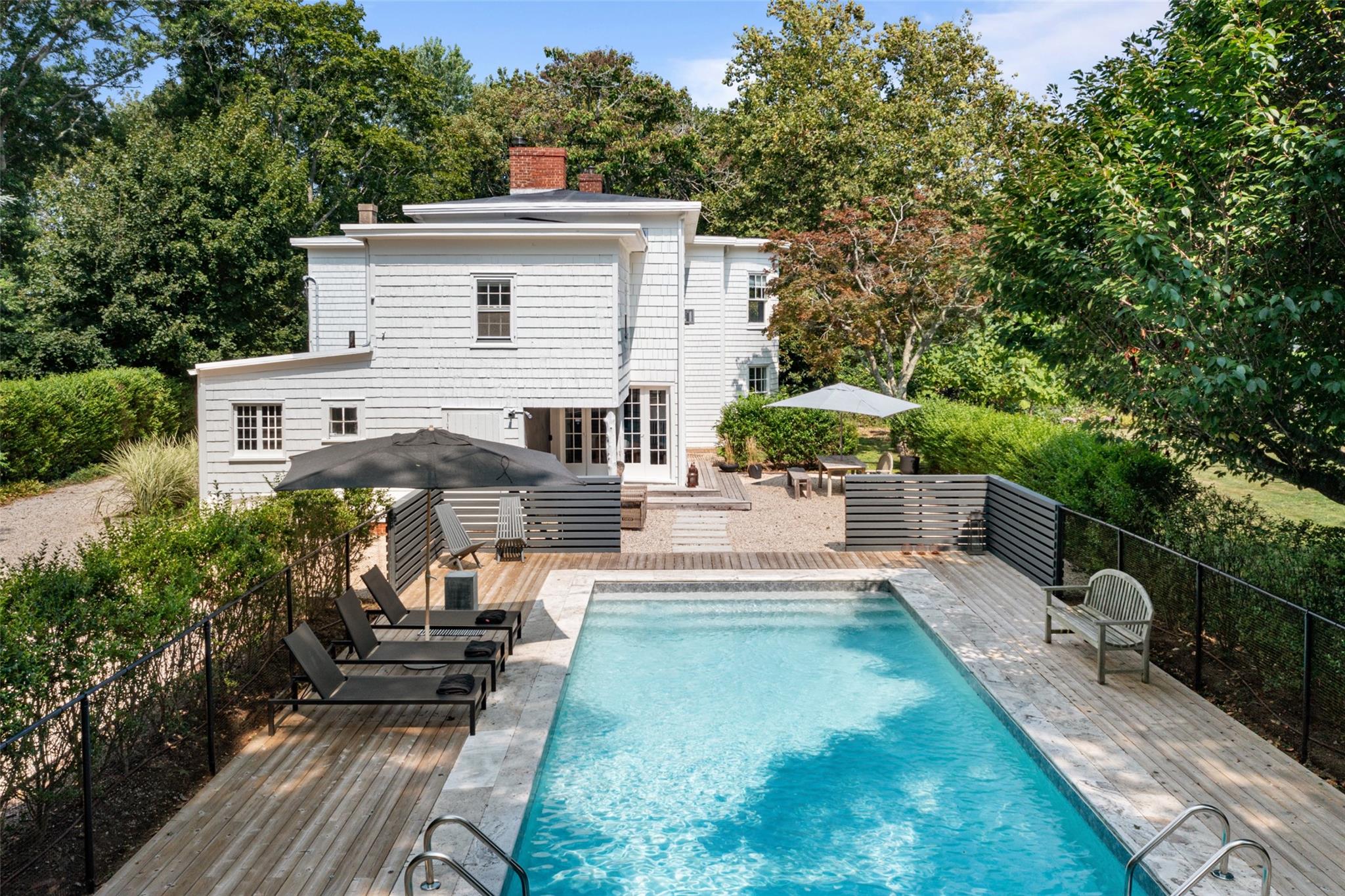 View of swimming pool featuring french doors, a wooden deck, and view of wooded area