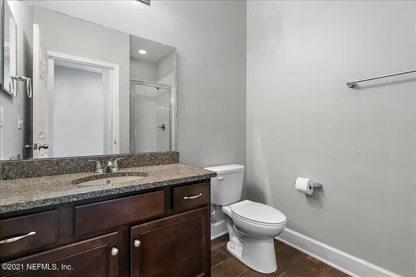 a bathroom with a granite countertop toilet sink and mirror