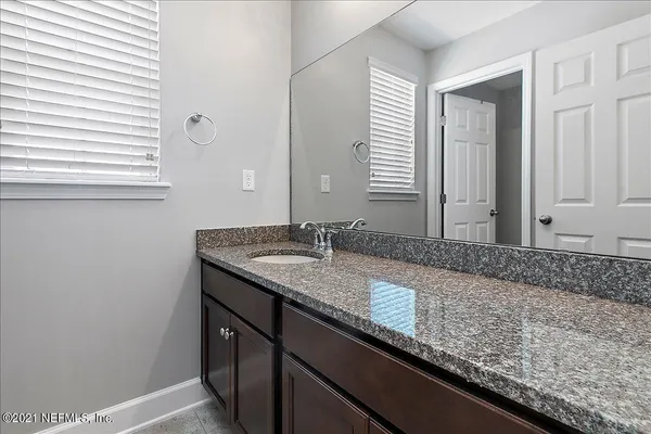 a bathroom with a granite countertop sink and a mirror