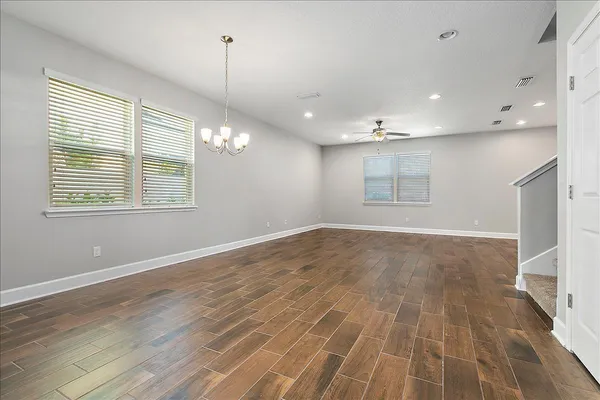 a view of empty room with wooden floor and fan
